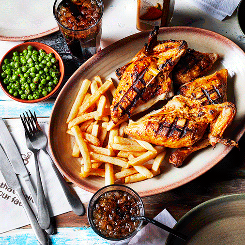 Food videography showing a plate of griddled chicken breasts and chips, with peas on the side and a cola drink
