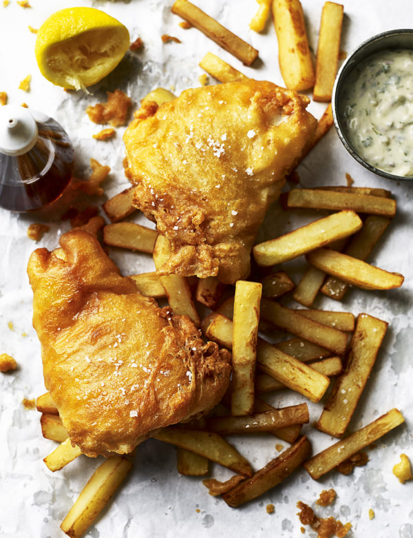 Food photography showing deep fried fish laid on a bed of chips
