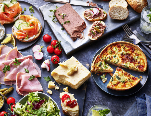Food photography showing a platter of pate, cooked meats, cheese, quiche and salad